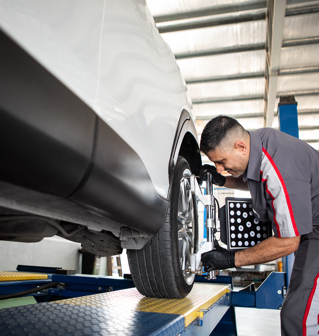 Mechanic aligning car wheels in garage.