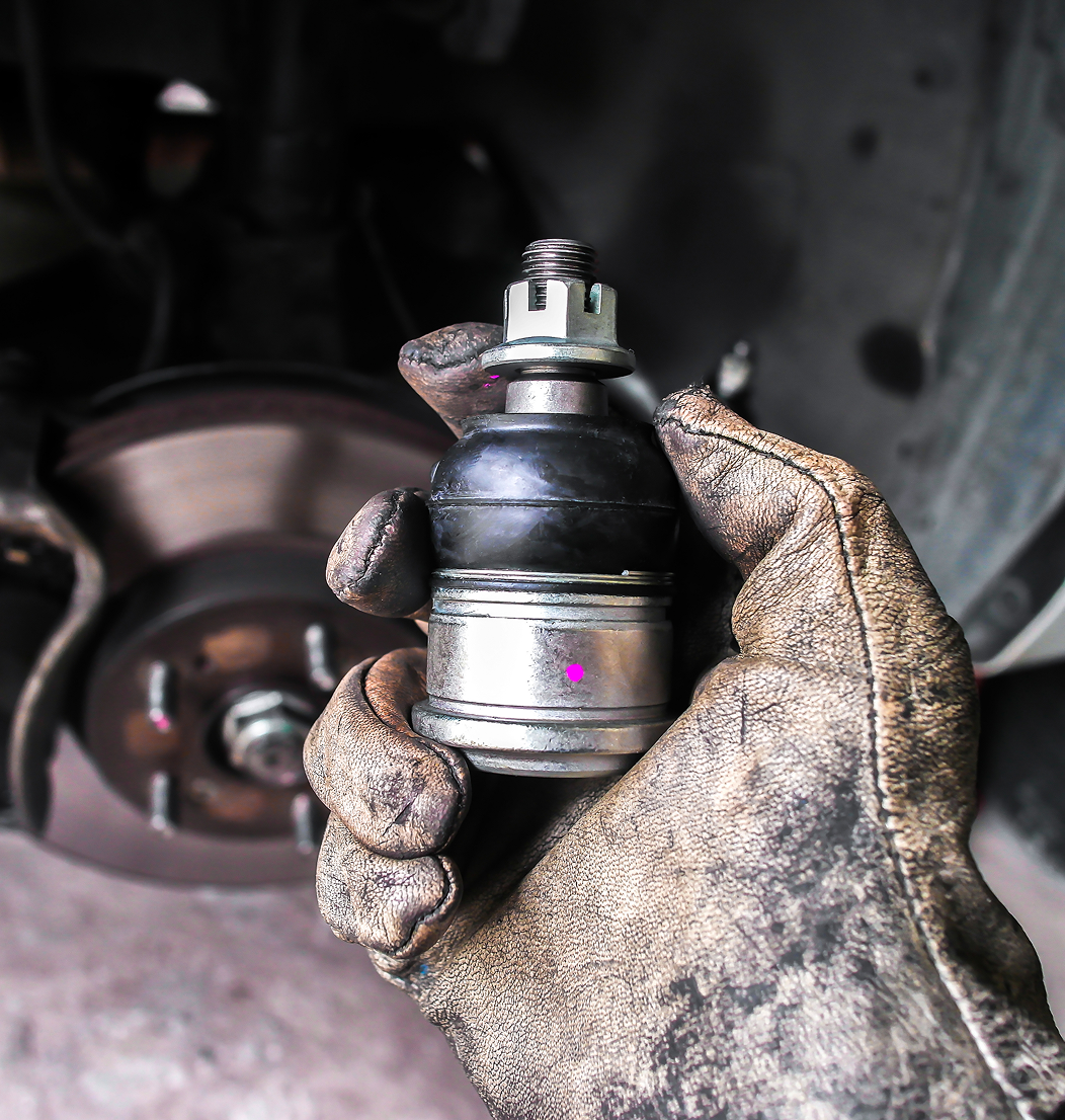 Gloved hand holding a car ball joint.