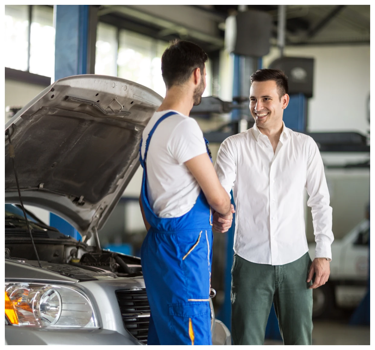 Mechanic and customer shaking hands in garage.